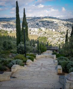 View from the Haas promenade in Jerusalem shows stone steps and cypresses with the old city in the distance