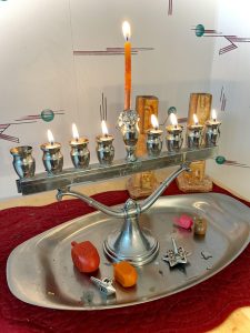 A silver menorah with oil flames and dreidels on a silver colored tray